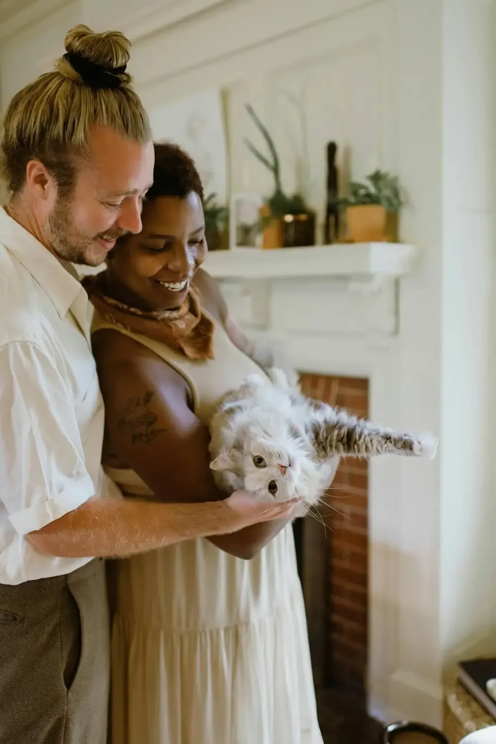 two individuals happily hold a cat together