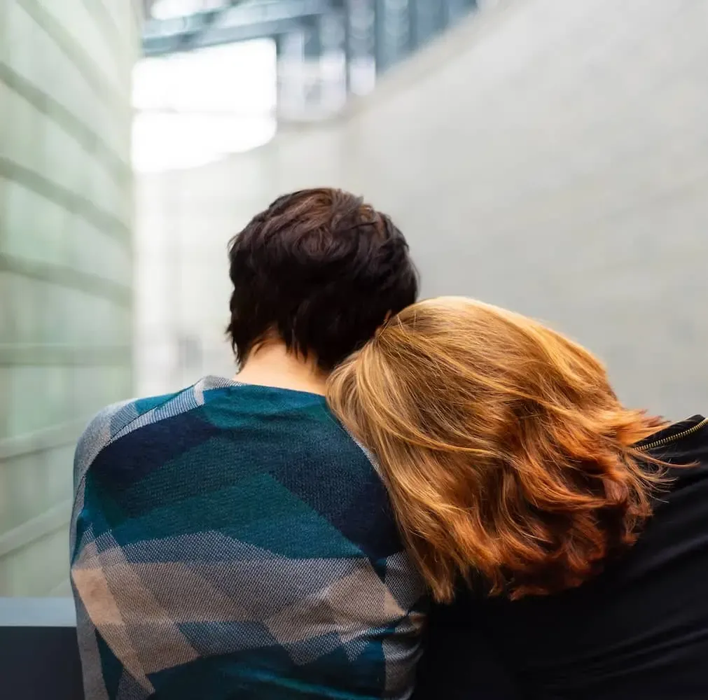 a person rests their head on another person's shoulder