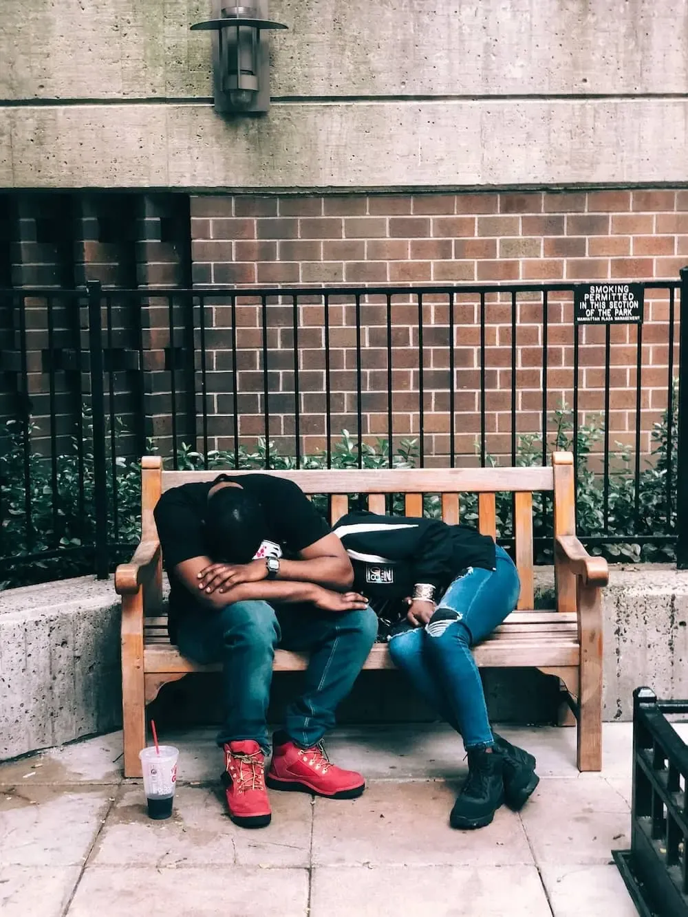 two individuals struggling to rest on a bench